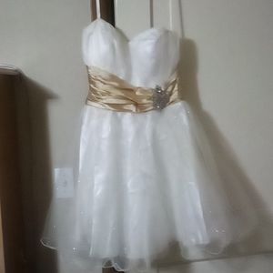 A short white dress with glitter on it and a gold belt like thing made onto it 9